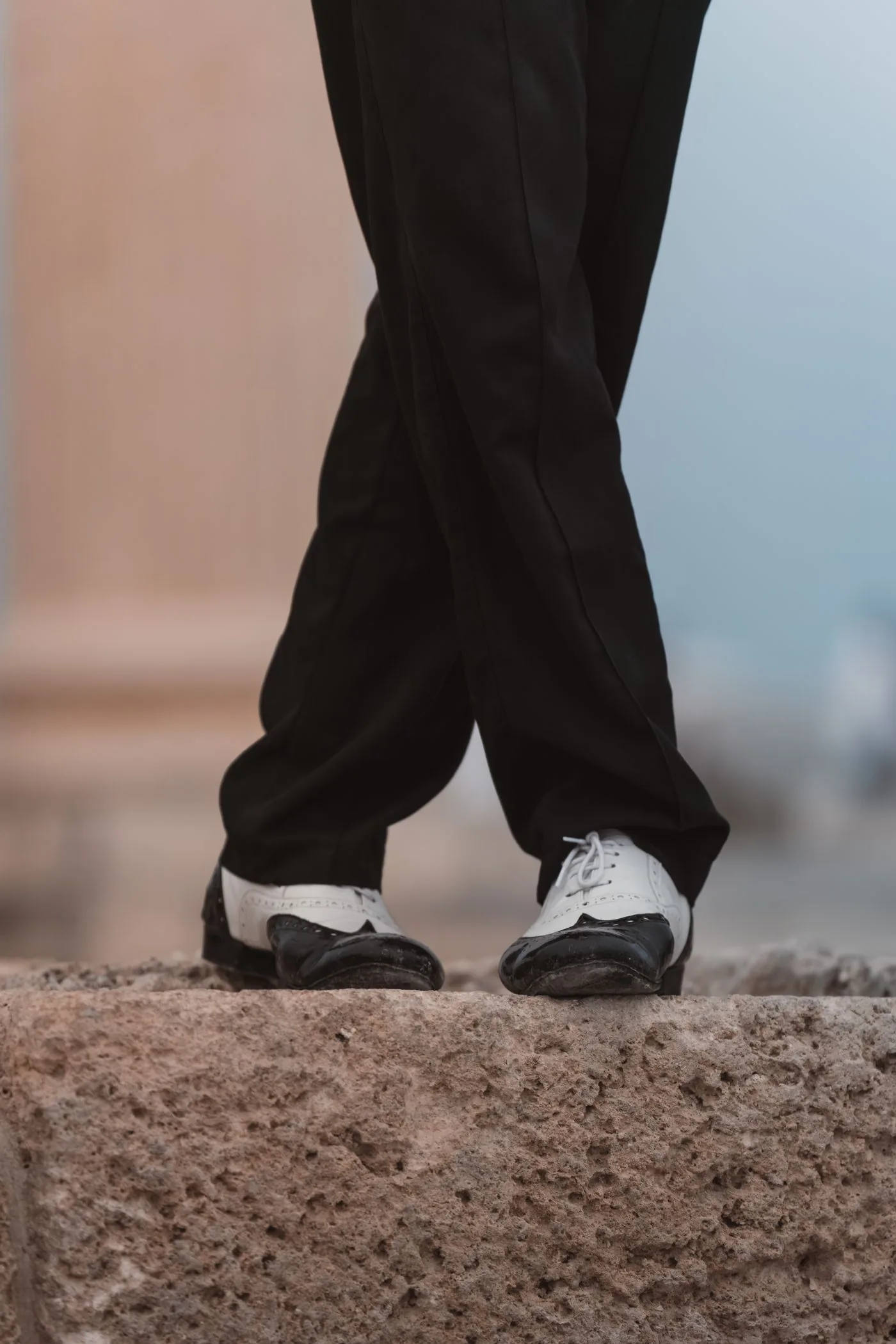 Schwarzweiße Steppschuhe auf hellem Stein